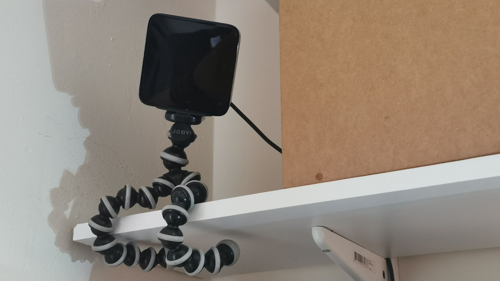 Una foto de una estación de seguimiento de Vive.  Está conectado a un estante con un trípode de cámara flexible.
