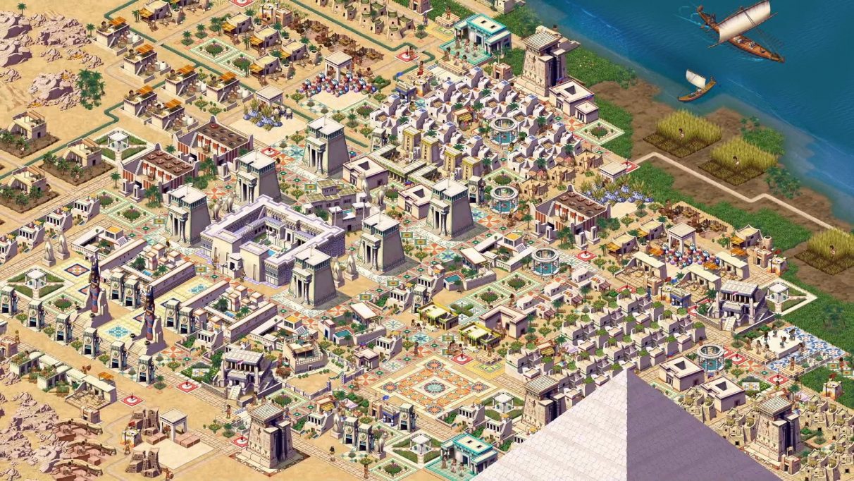 Una segunda captura de pantalla promocional de una ciudad en Pharaoh: A New Era.  Esta ciudad es más grandiosa.  Las orillas del Nilo son visibles en la esquina superior derecha, y la punta de una pirámide asoma desde la parte inferior de la captura de pantalla.