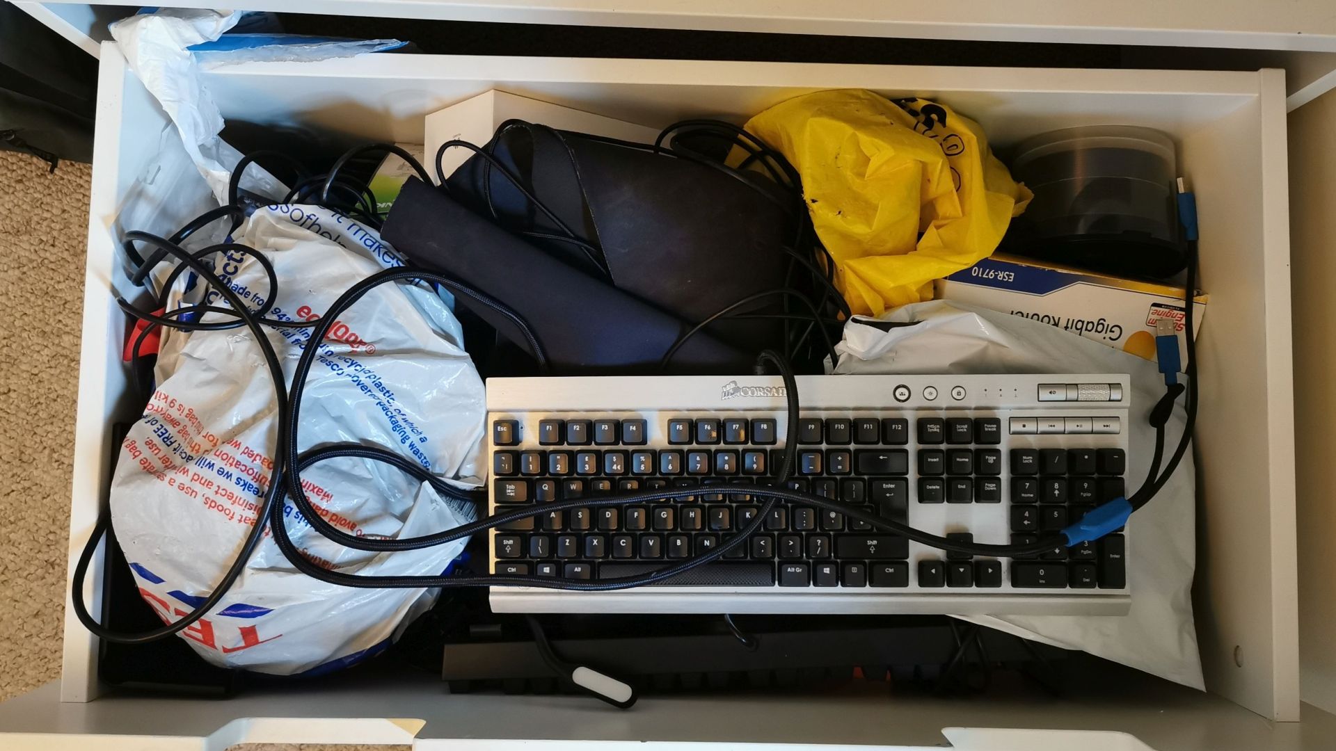 Una fotografía de un dibujo lleno de piezas de PC: un teclado, una pila de CD, varios cables, bolsas de plástico con gubbins desconocidos.